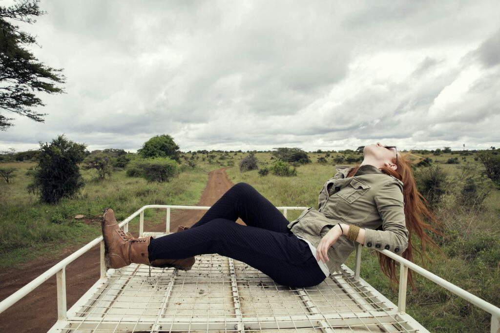 Traveller enjoying ride on top of vehicle in wildlife park, Nairobi, Kenya